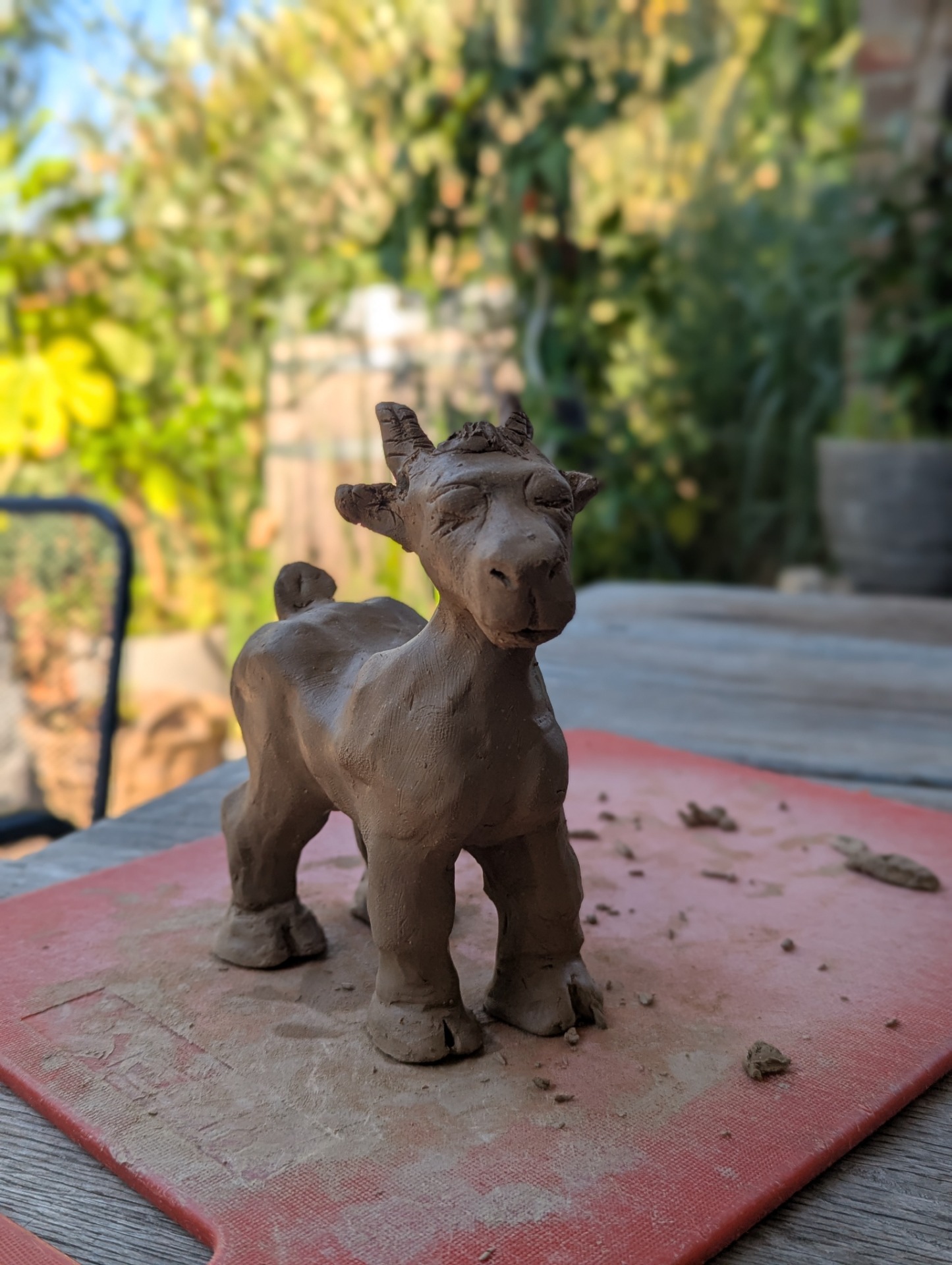 Handgeformte Tonziege auf einem Gartentisch.
