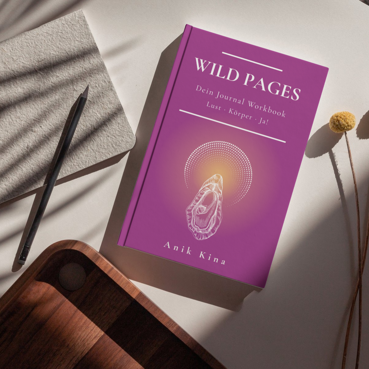 Lila Journalbuch „Wild Pages“ auf Tisch, daneben Stift, Stoff und Holzschale im Sonnenlicht.